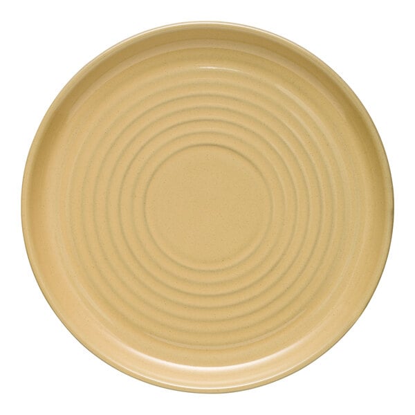 A close up of a Libbey tan stoneware plate with spiral lines on a white surface.