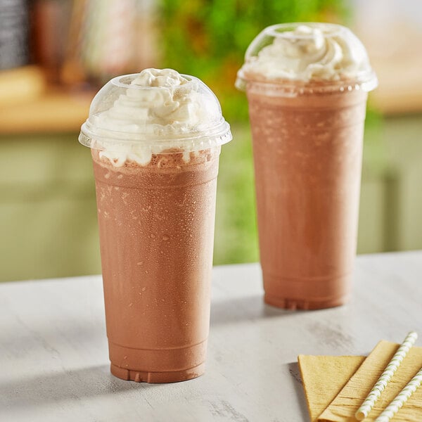 Two Choice clear PET plastic cold cups with chocolate milkshakes and straws with dome lids and straws.
