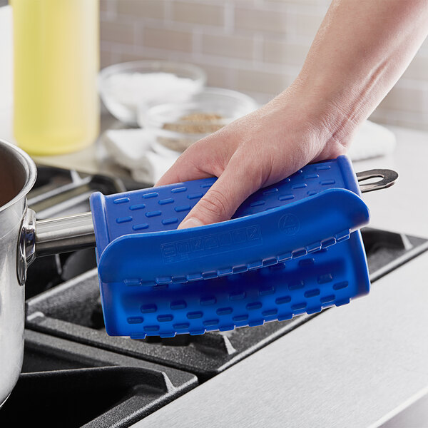 A hand holding a blue Araven silicone pot holder over a pot.