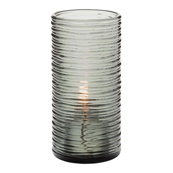 A Hollowick Typhoon smoke glass cylinder candle holder with a lit candle inside.