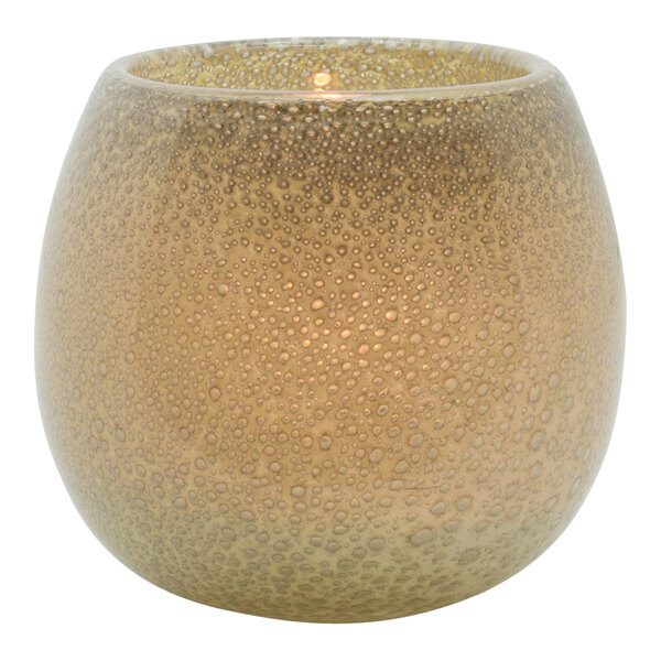 A close-up of a Hollowick Sepia Art Glass Votive with a lit candle inside.