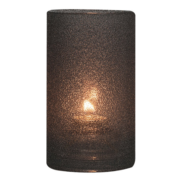 A lit black Hollowick Silo glass candle lamp on a table.