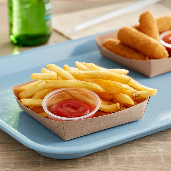 Two Kraft paper trays of fries with ketchup on a table.