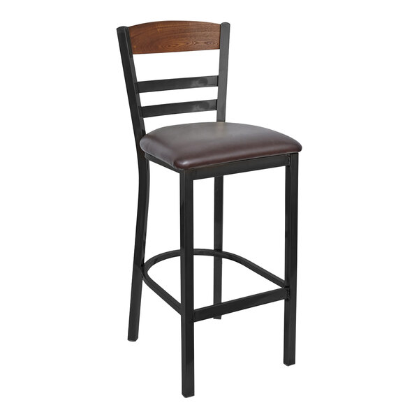 A BFM Seating black steel barstool with a dark brown vinyl seat and brown wood back panel.