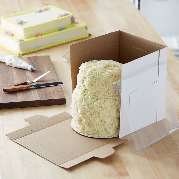 A white cake with yellow and purple frosting in an Enjay Flexbox bakery box.