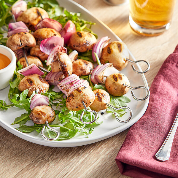 A plate with Choice stainless steel round skewers of meat and vegetables on a table.