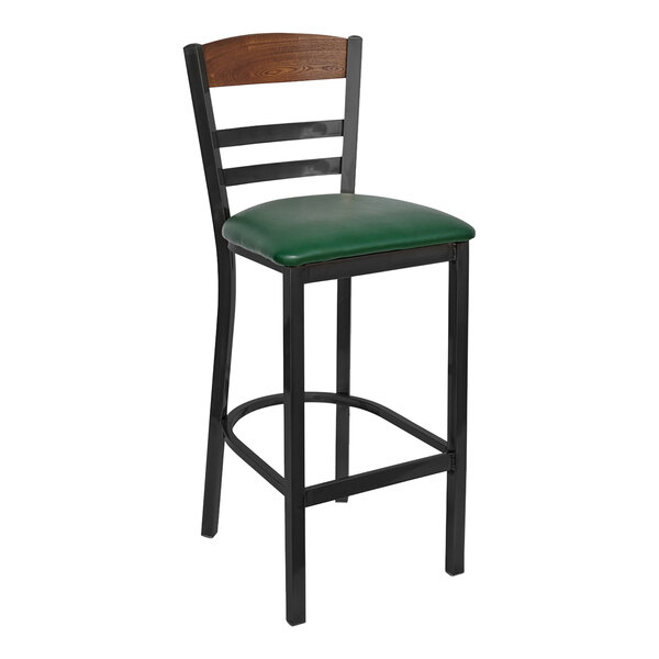 A BFM Seating black steel bar stool with a green vinyl seat and wood back panel.