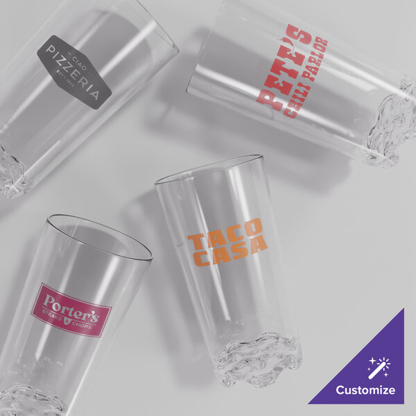 A set of four clear plastic highball glasses, each with a different customizable logo printed on the side.
