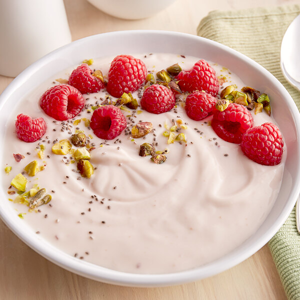A bowl of Pequea Valley Farm raspberry yogurt with raspberries and nuts.