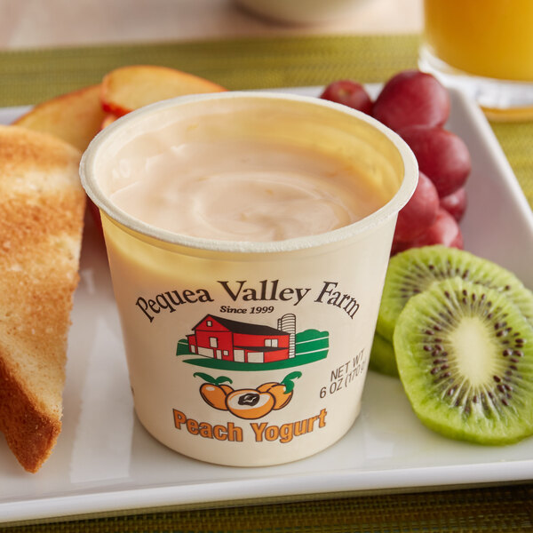 A cup of Pequea Valley Farm peach yogurt with fruit on a plate.