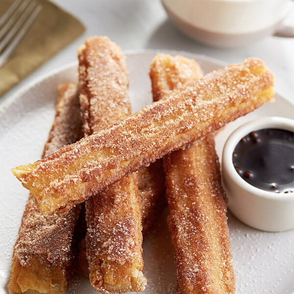 White Toque fried churros on a plate with dipping sauce.