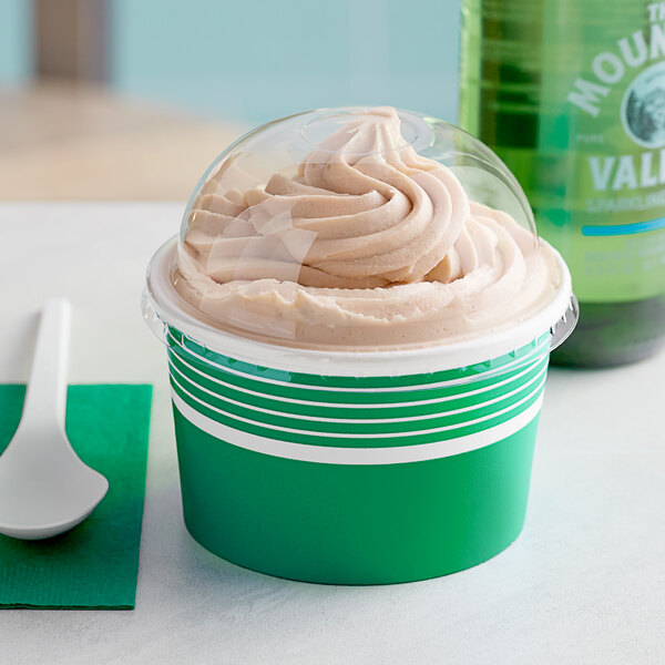 A close up of a Choice green paper frozen yogurt cup with a dome lid filled with ice cream and a spoon.