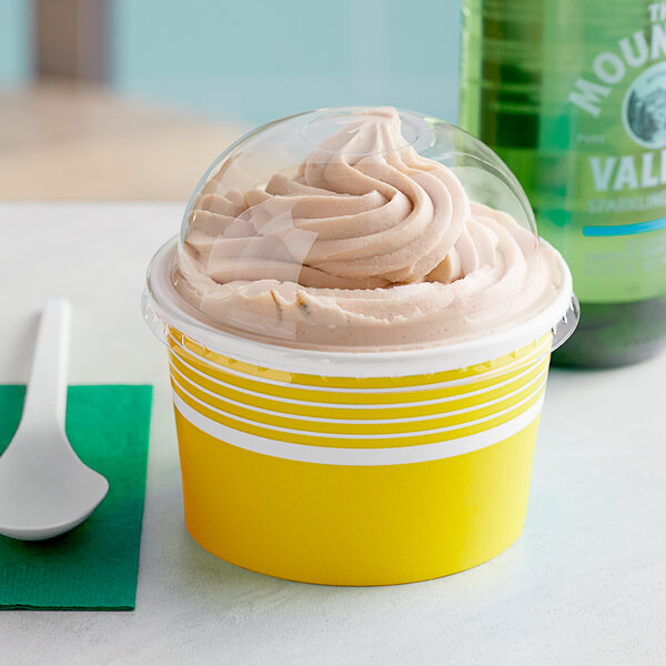 A yellow Choice paper frozen yogurt cup with a dome lid full of frozen yogurt.