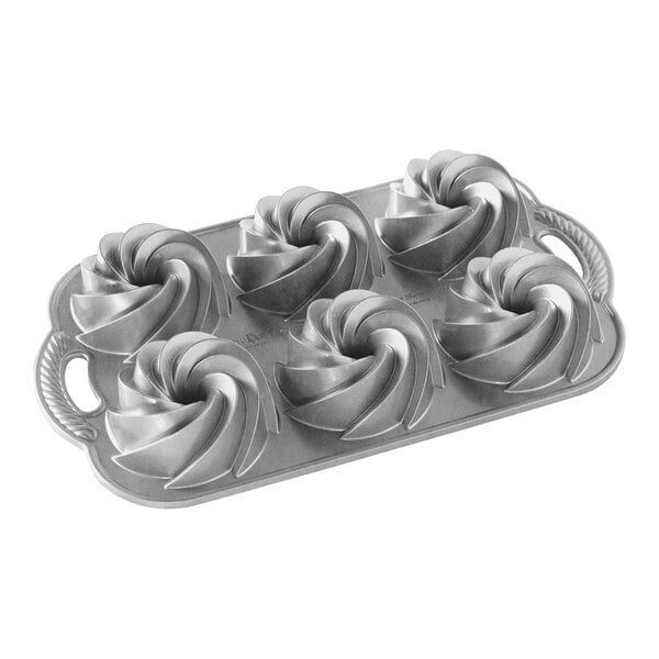 A Nordic Ware metal cake pan with six swirl-shaped mini cake pans.