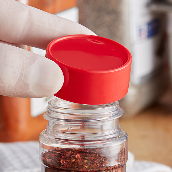 A person holding a jar with a red unlined polypropylene spice cap on it.