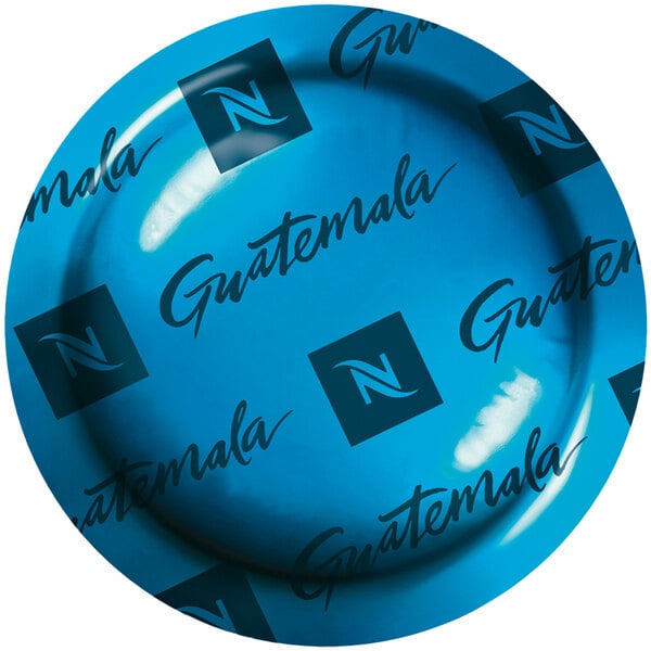 A blue Nespresso box of Guatemala coffee capsules on a table with a blue plate with black text saying "Guatemala" on it.