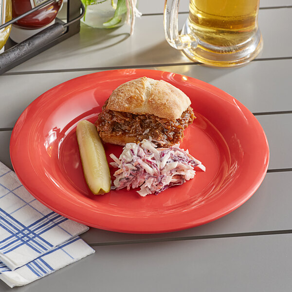 An Acopa orange melamine plate with a sandwich and coleslaw on a table outdoors.
