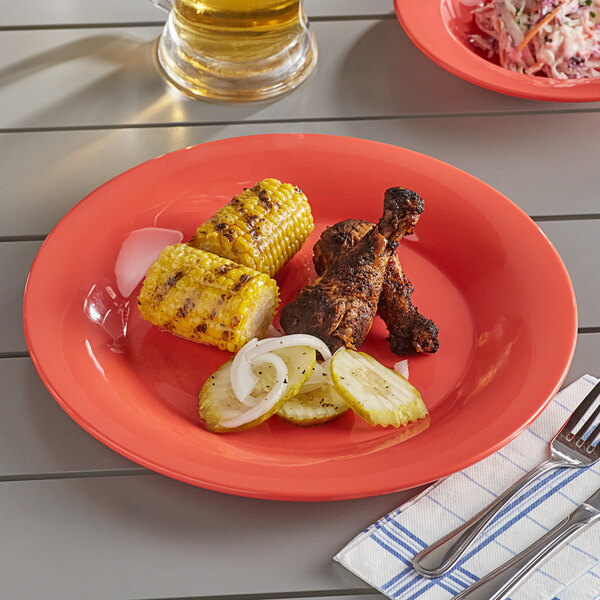 An Acopa Foundations orange melamine plate with grilled chicken and corn on a table.