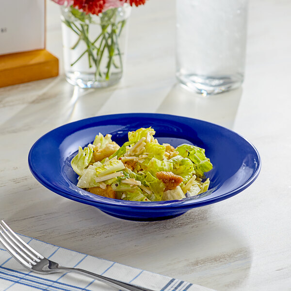 An Acopa Foundations blue melamine bowl filled with a salad on a table.