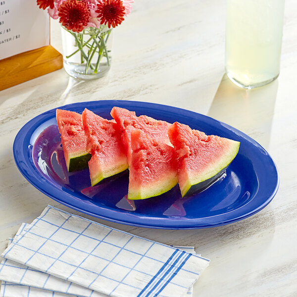 A blue Acopa Foundations melamine platter with watermelon slices on a table.