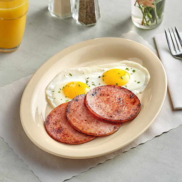 An Acopa tan melamine platter with eggs and sausage on it.