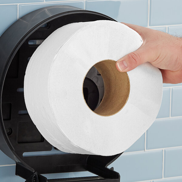 A hand holding a Morcon Morsoft jumbo toilet paper roll.