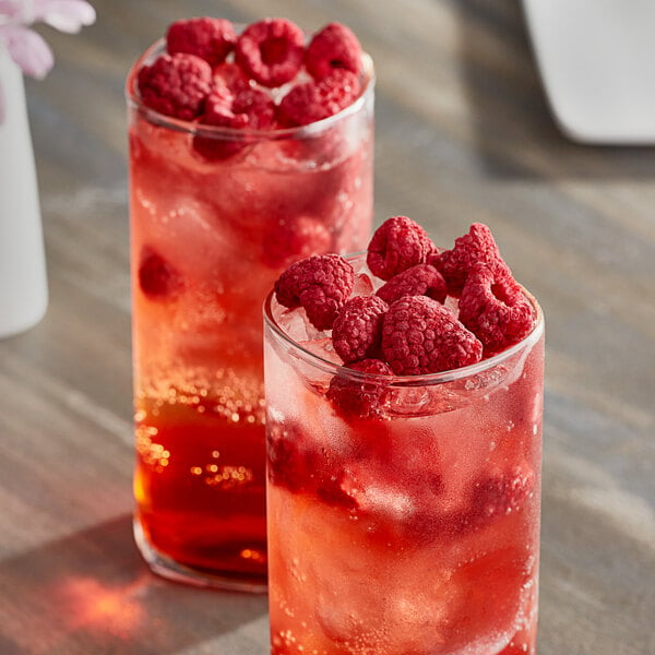 Two glasses of raspberries and ice.