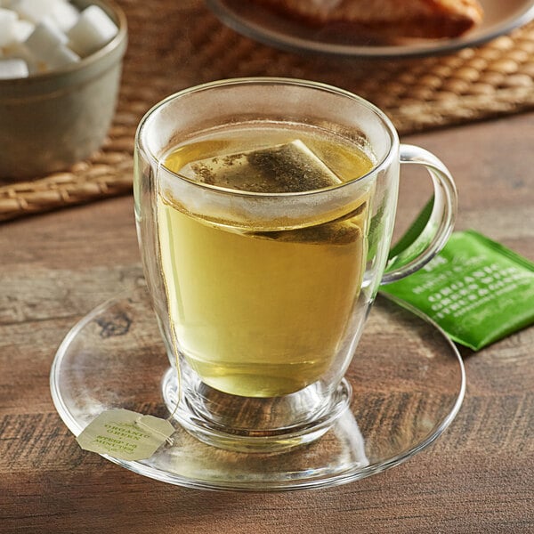 A glass cup of Harney & Sons green tea with a tea bag in it.