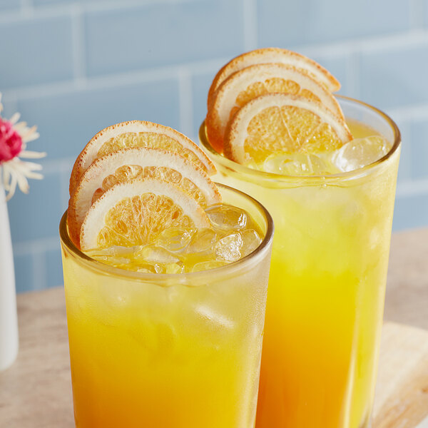 A glass of orange juice with ice and Mixologist's Garden freeze-dried orange slices.