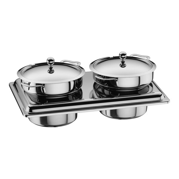 Two WMF stainless steel soup tureens with lids on a tray.
