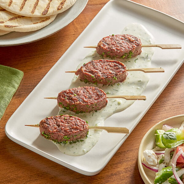 A plate of Black Sheep Foods plant-based lamb kebabs with a salad on a table.