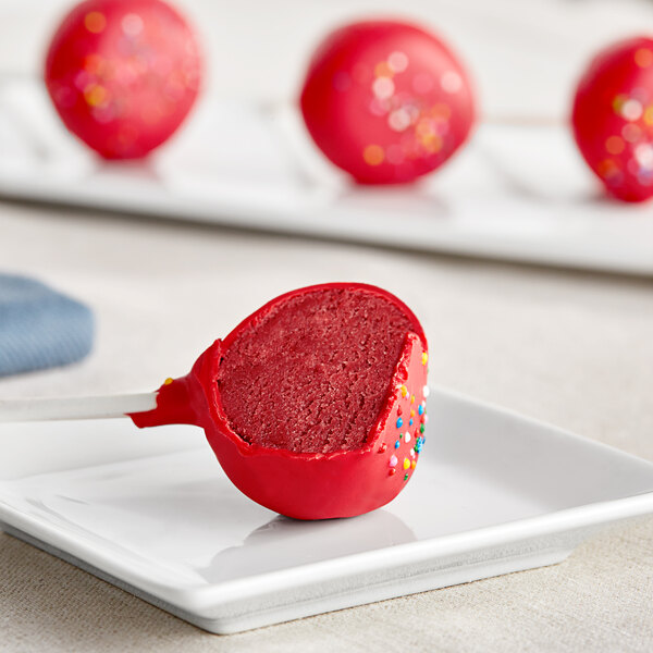 A red Coco Bakery red velvet cake pop on a white plate.