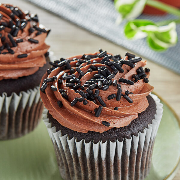A cupcake with chocolate frosting and Supernatural Chocolate Softies sprinkles on a counter.