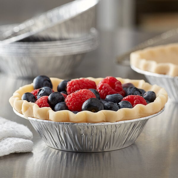 A Baker's Lane foil tart pan with a pie and berries.