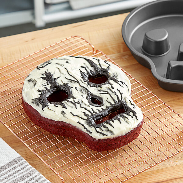 A cake with frosting in the shape of a skull on a cooling rack.