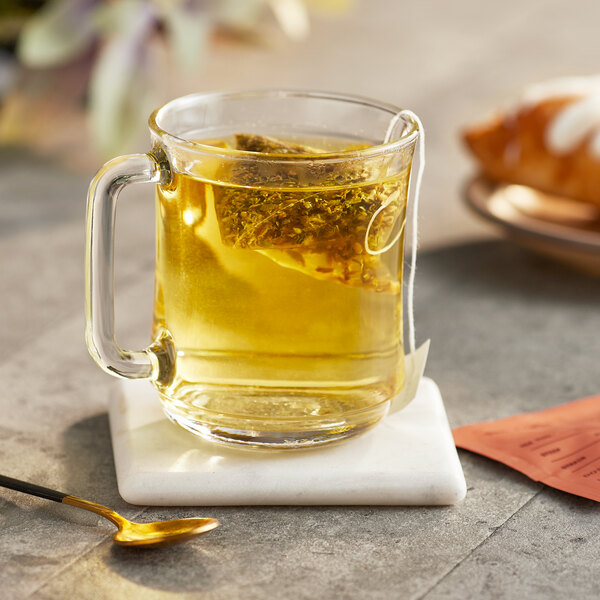 A glass mug of Dona Field Herbal Tea with a bag of tea in it.