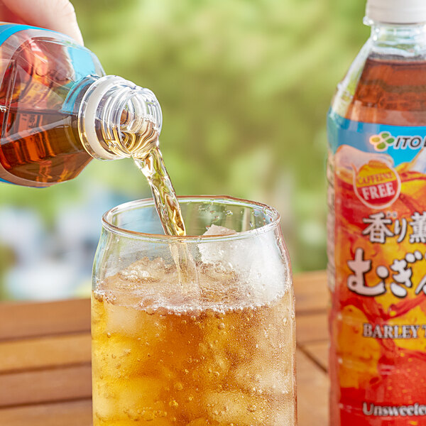 A hand pouring Ito En Mugicha Barley Iced Tea from a bottle into a glass.