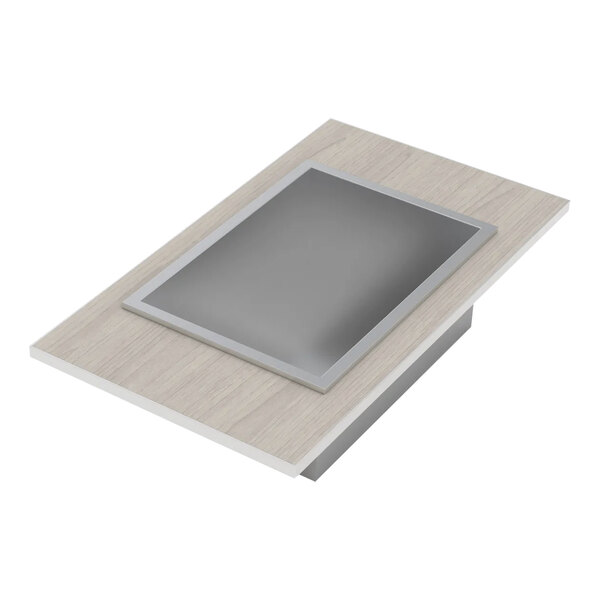 A rectangular Bon Chef drop-in cold food well with a silver frame on a table.