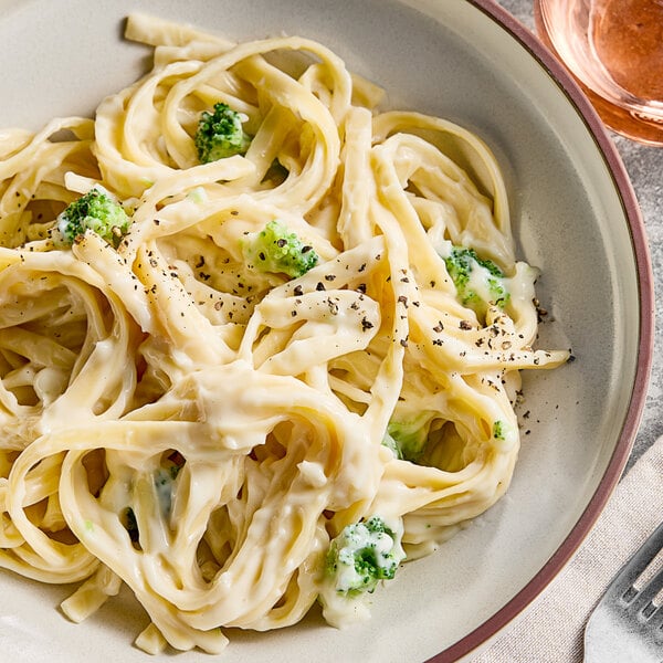 A plate of pasta with broccoli and Trio Alfredo sauce.