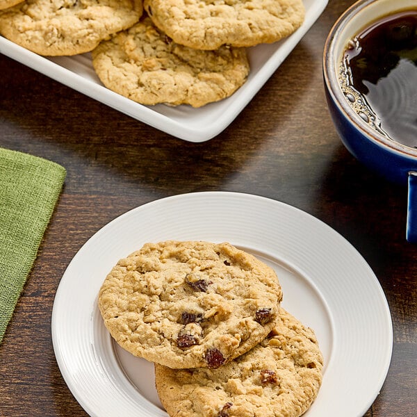 A plate of Otis Spunkmeyer Oatmeal Raisin cookies next to a cup of coffee.