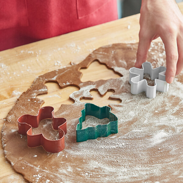 A person using Wilton holiday cookie cutters to make cookies.