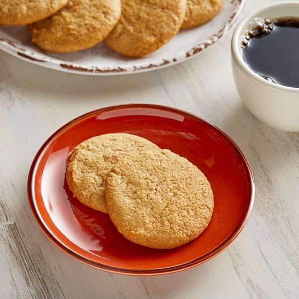 A plate of Otis Spunkmeyer whole grain sugar cookies on a wood table with a cup of coffee.