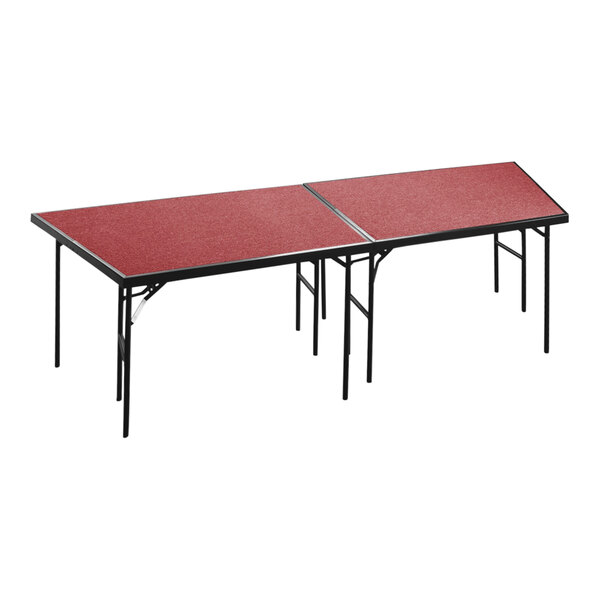 A red rectangular National Public Seating stage pie table with black legs.