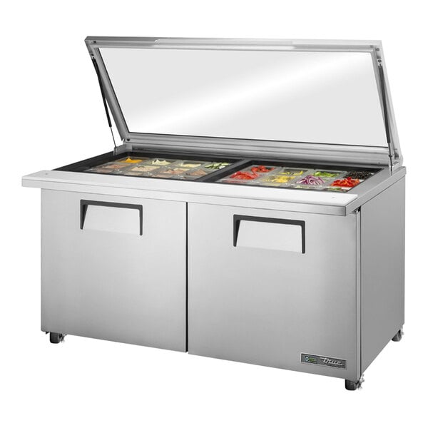 A True stainless steel refrigerated sandwich prep table with a glass top over a mega top.