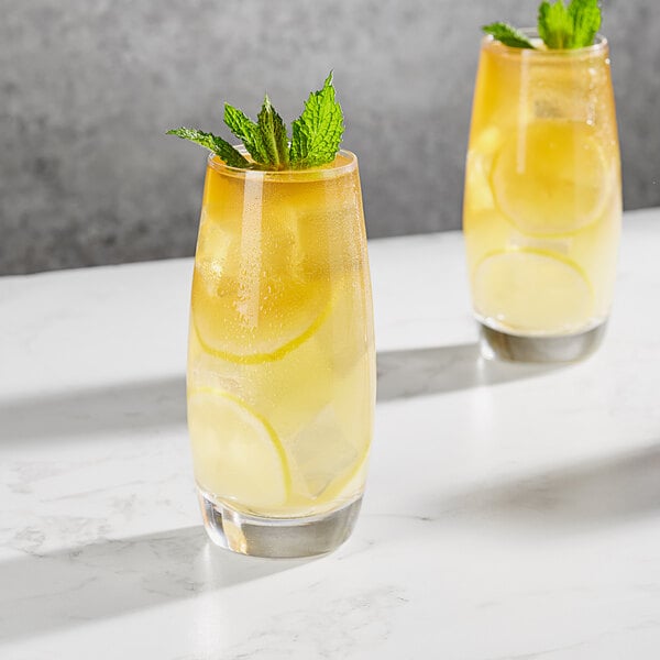 Two Della Luce Avalon beverage glasses of lemonade with lemons and mint leaves.