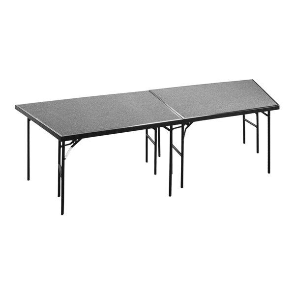 A gray National Public Seating carpeted stage pie on a table with two legs.