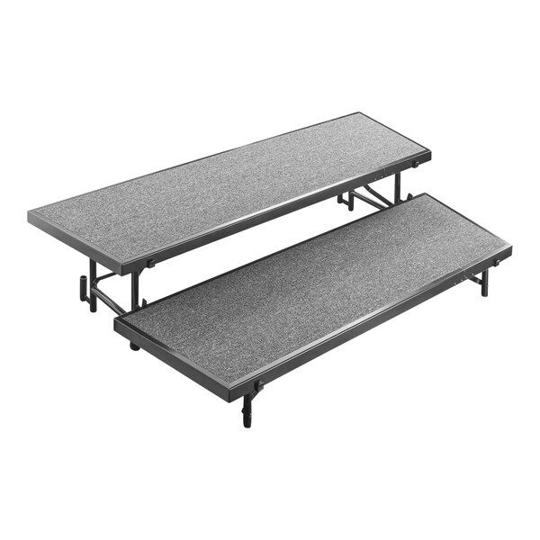 A National Public Seating grey carpeted choral riser with black legs.