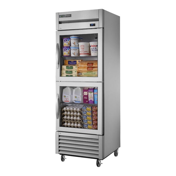A True stainless steel reach-in refrigerator with half glass doors full of food.