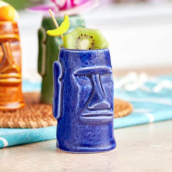 An Acopa blue ceramic tiki shot glass with a fruit on it.