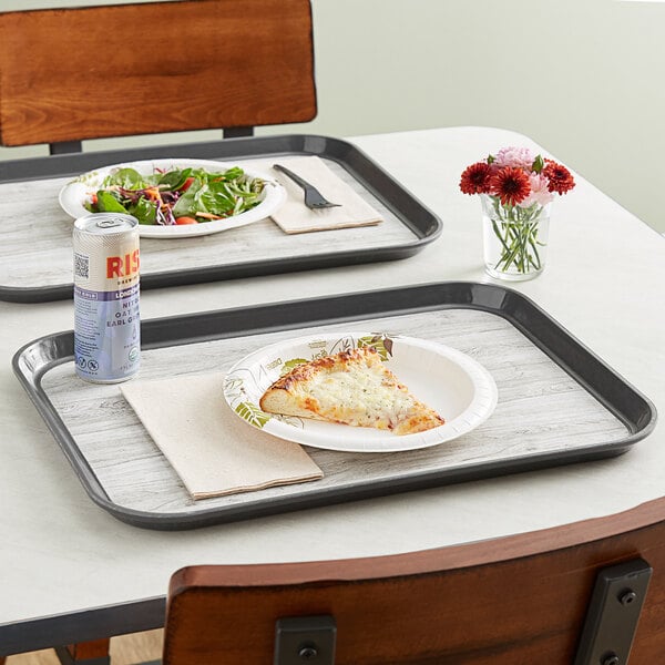 A Dinex woodgrain tray with a pizza and salad on it on a table.